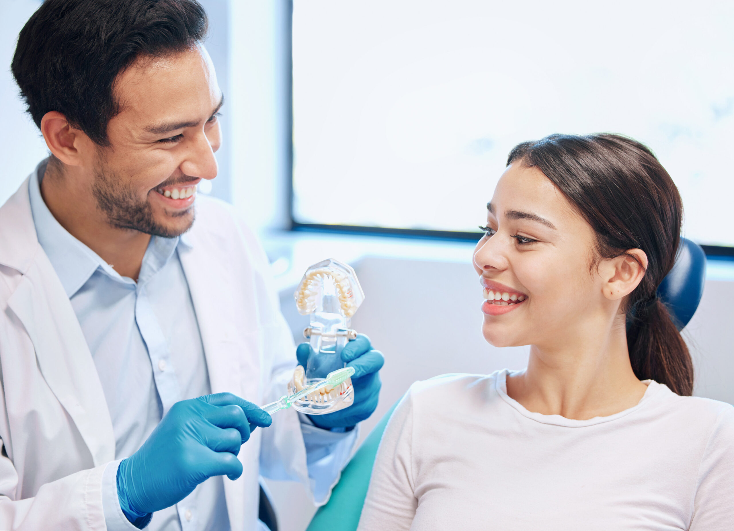 Dentist, woman and dental mould for hygiene demonstration with toothbrush, cleaning or brushing teeth. Smile, doctor and patient for oral healthcare, education and expert advice for whitening results.